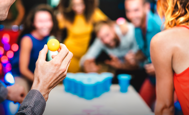 Menschen spielen ein Becher-Ballspiel bei einer Feier, fröhliche Stimmung.