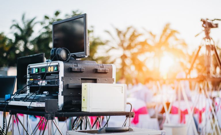 Technische Ausrüstung und Kameras bei einer Veranstaltung im Freien bei Sonnenuntergang.