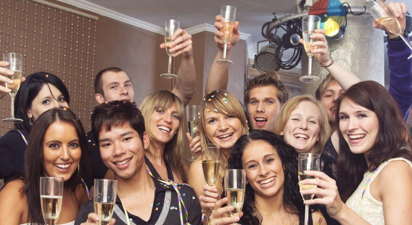 Junge Menschen stoßen mit Champagnergläsern auf eine Feier an.