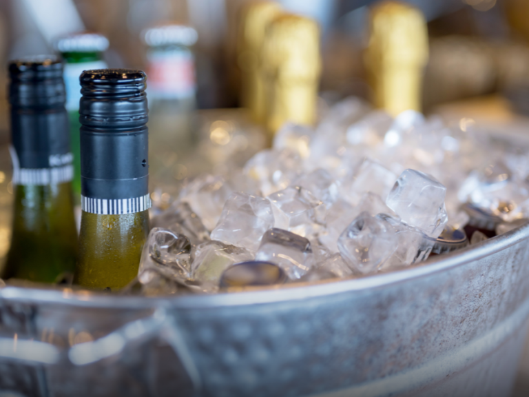 Flasche mit Sekt und Eis in einem silbernen Eimer, dekorativ angeordnet.