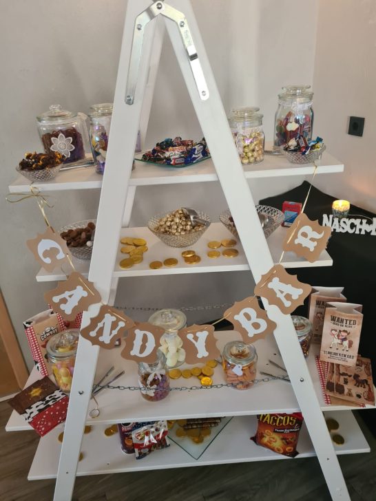 Ein weißes Regal mit Süßigkeiten und einem „Candy Bar”-Schild.